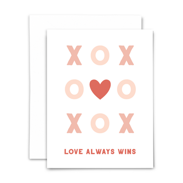"Love always wins" greeting card; tic tac toe game of pink Xs and Os with red heart in the center on white background; blank interior with white envelope