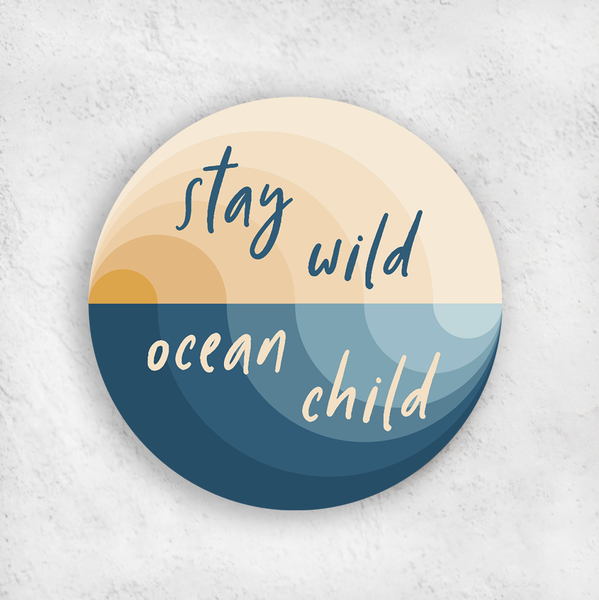 Stay wild ocean child vinyl sticker; concentric semi-circles in blue and gold hues create the illusion of a beach wave with a sunset above; handwritten font