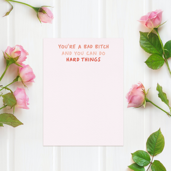 You're a bad bitch and you can do hard things in handwritten coral font on pink background; 10 flat notecard set with envelopes shown on white wood background with pink roses