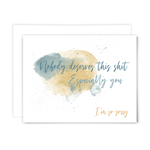 'Nobody deserves this ish. Especially you. I'm so sorry' greeting card with blank interior; blue font on white card with watercolor splashes in the background