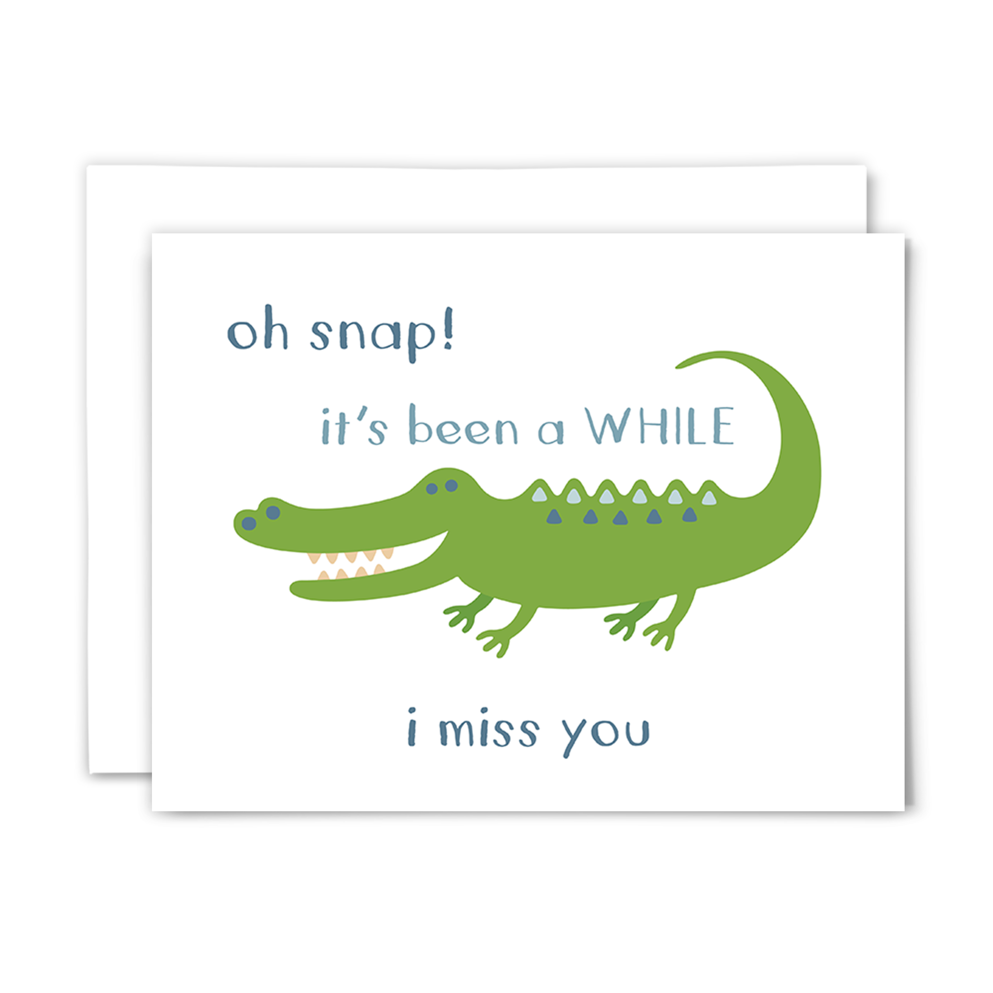 Folded A2 greeting card with blank interior and white envelope; front reads ""oh snap! it's been a WHILE ~ i miss you" with a big, green, cartoon crocodile with a big toothy smile on a white background