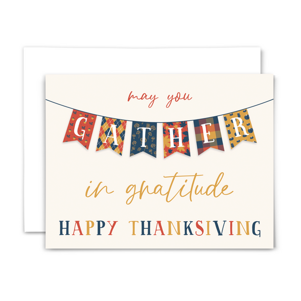 Thanksgiving greeting card "may you gather in gratitude ~ happy thanksgiving" in red, gold and navy blue fonts on cream background with "gather" in banner stretching horizontally across card with autumn patterns; with white envelope