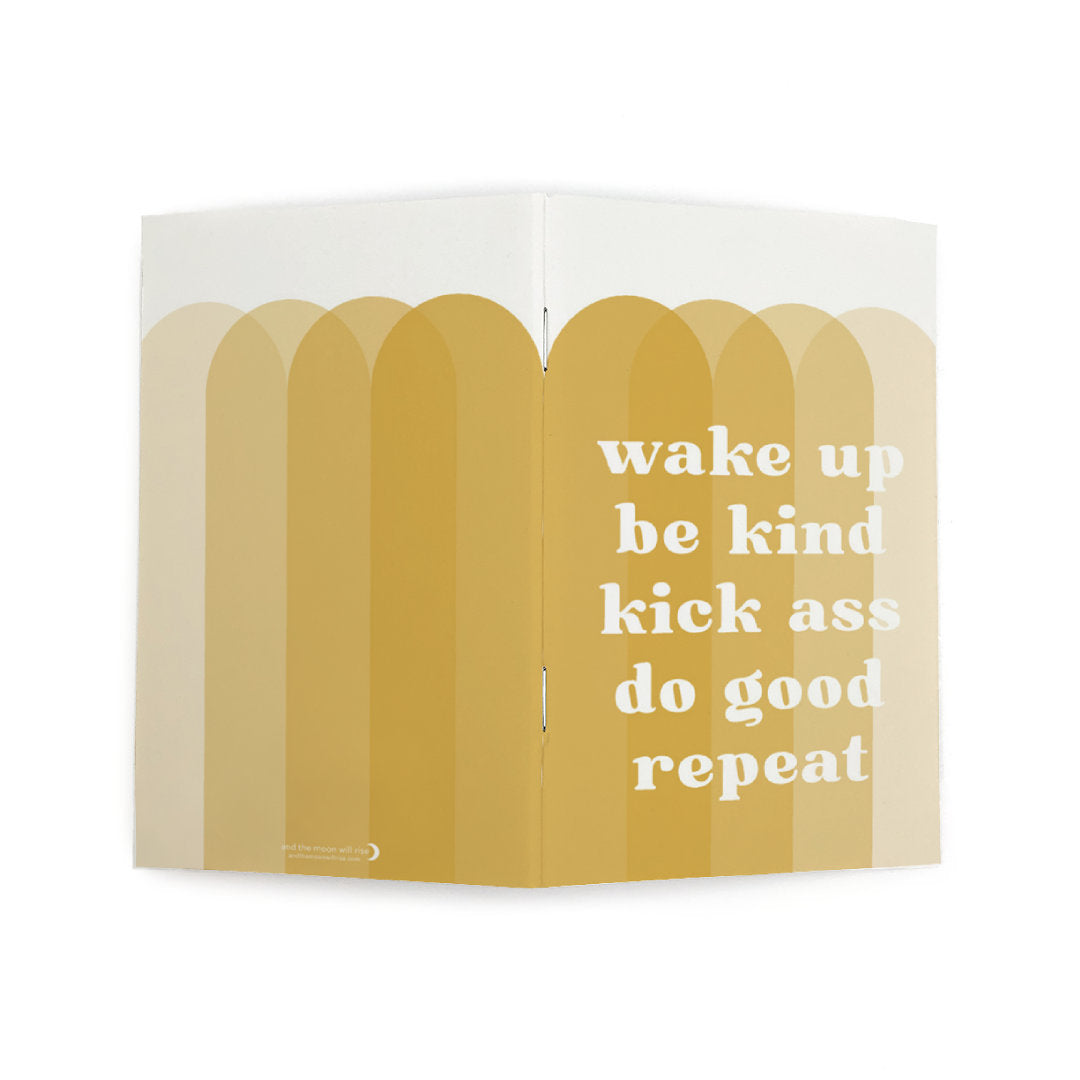 Front and back cover of dot grid pocket notebook with large white text WAKE UP BE KIND KICK ASS DO GOOD REPEAT atop 4 overlapping vertical arches in various shades of gold