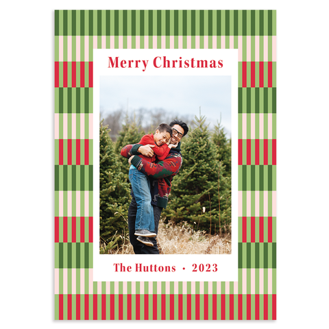 Custom holiday photo card; single vertical photo with white border and holiday greetings in red atop checkered background in shades of green and red; 7" x 5" vertical orientation; fully customizable back