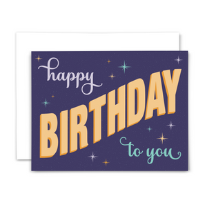 Retro-style birthday greeting card "happy birthday to you" in purple, teal and yellow fonts on dark purple background with colorful stars and light purple dots; with white envelope