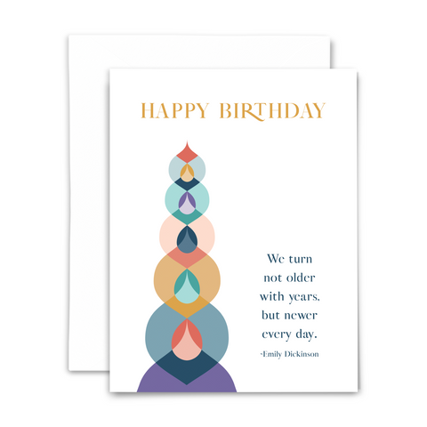 Happy birthday greeting card with blank interior; text reads "happy birthday" with quote from Emily Dickinson "we turn not older with years, but newer every day"; white card with colorful geometric shapes; with white envelope
