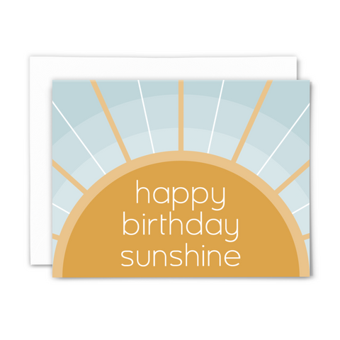 blank greeting card, "happy birthday sunshine" in white sans-serif font on golden sun with rays over concentric blue arches with white envelope