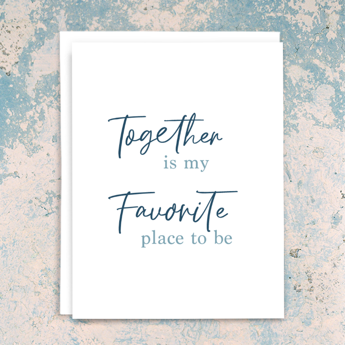 "Together is my favorite place to be" greeting card; dark blue script and light blue serif fonts on white background; blank interior with white envelope. Shown photographed on distressed blue and cream plaster background.